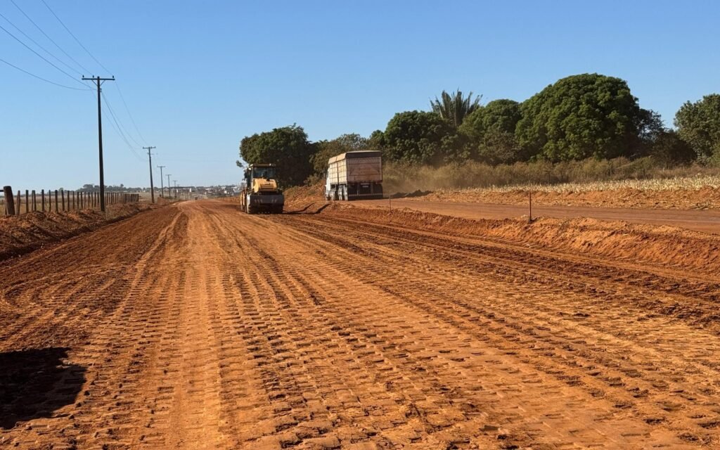 Trator e caminhão trabalhando em estrada de terra em processo de terraplenagem