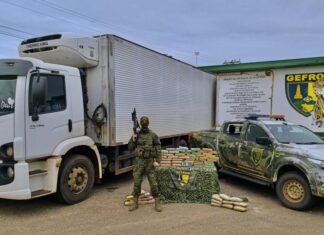 Agente do Gefron em frente a caminhão apreendido com tabletes de droga expostos