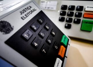 Eleitor votando em urna eletrônica em cabine de votação