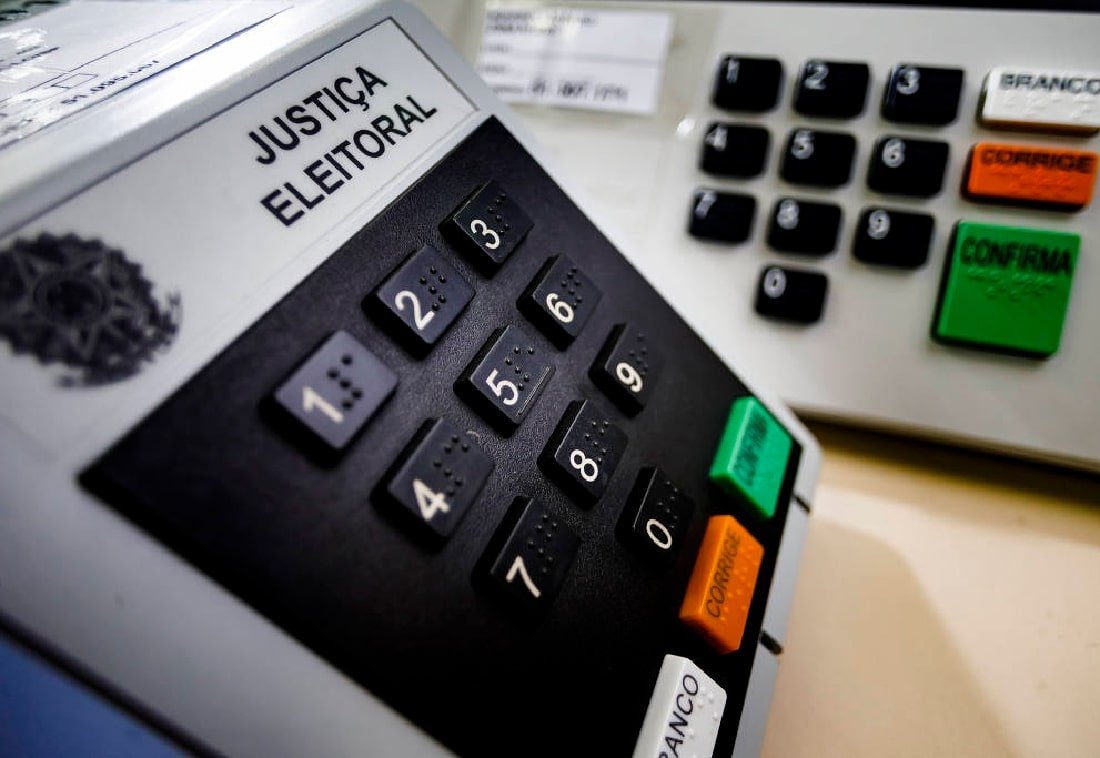 Eleitor votando em urna eletrônica em cabine de votação