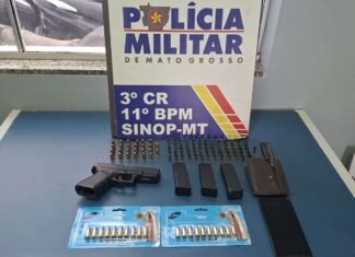 Pistola, carregadores e munições sobre mesa ao lado de identificação da Polícia Militar de Mato Grosso